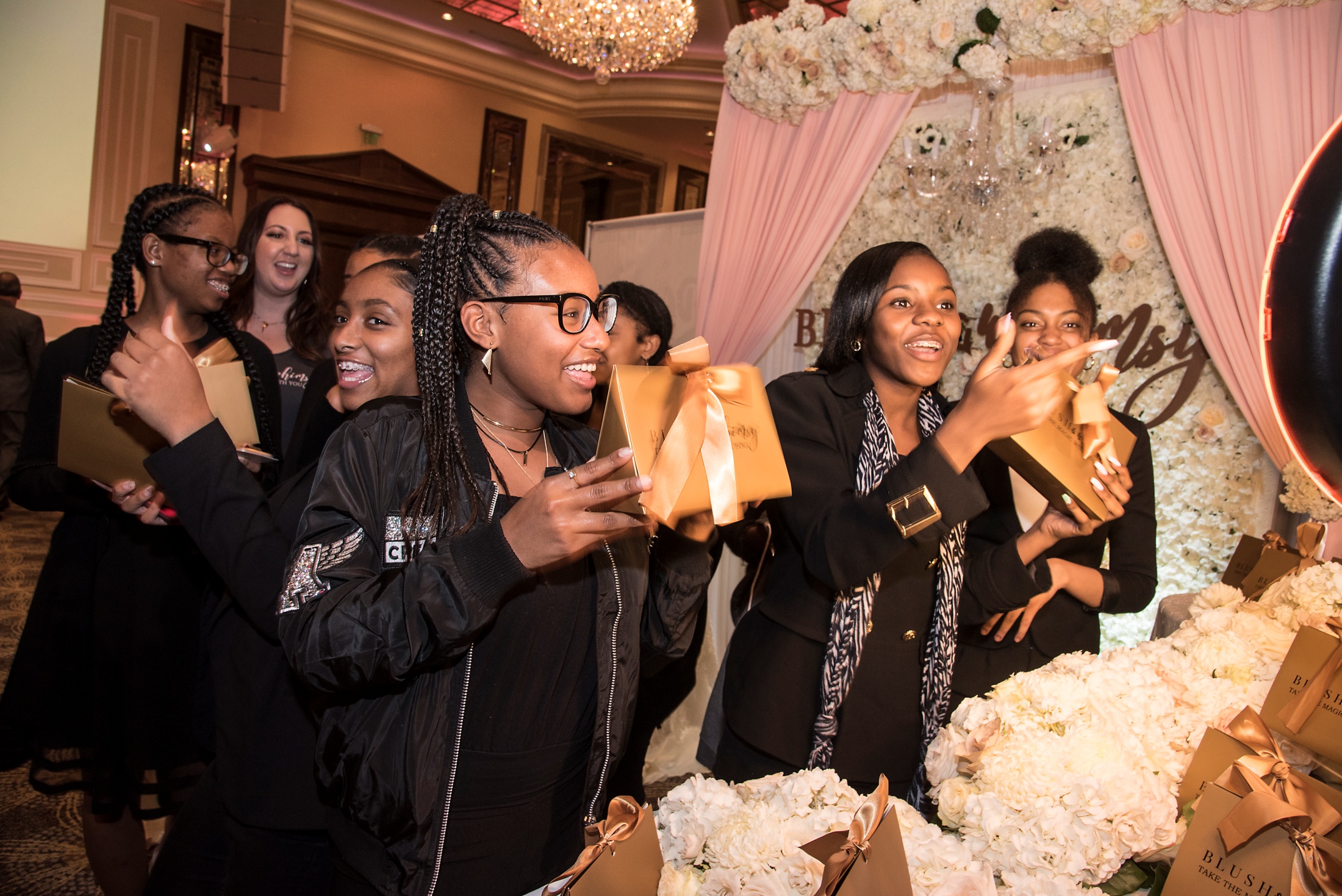 Guests holding Blush & Whimsy gift bags in front of the floral brand wall